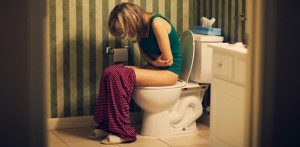 Woman in pain on toilet in bathroom
